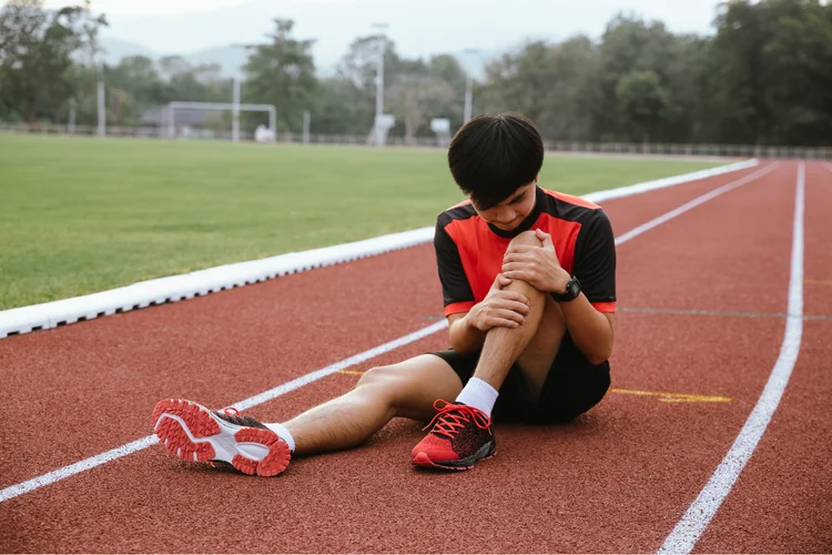 Athlete holding knee in pain after ACL injury.