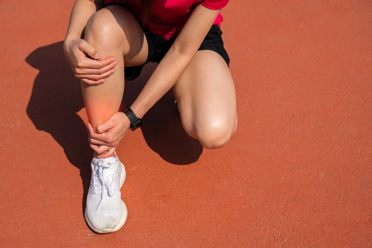 Athlete clutching shin from sports-related leg pain.