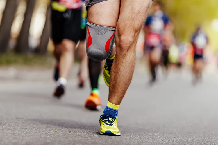 Athlete wearing knee brace during race to prevent patellofemoral pain and reduce joint stress.