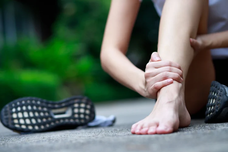 Close-up of runner holding ankle in pain showing common sports injuries such as sprains and strains.