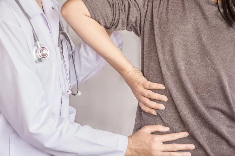 Specialist assessing woman's back to diagnose cause of back pain.
