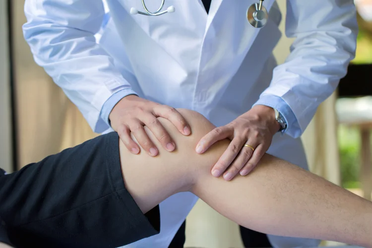 Doctor assessing anterior knee pain by checking for patella alignment and soft tissue irritation.
