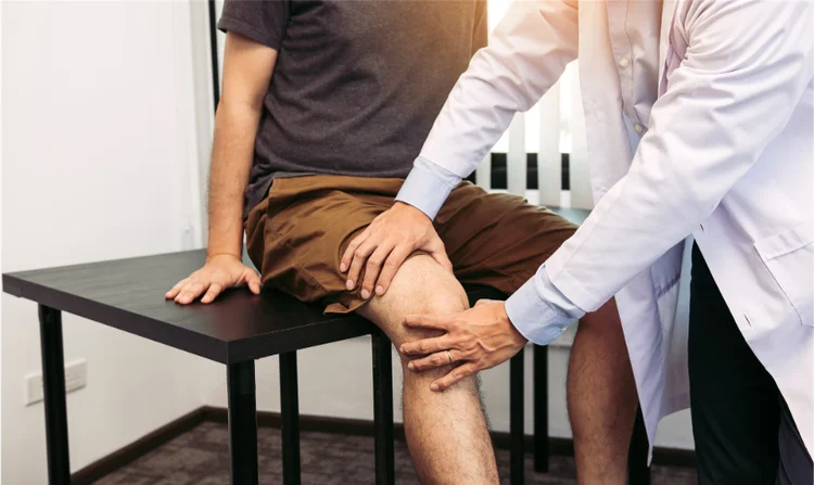 Doctor performing a physical examination on a patient with knee pain in Singapore, focusing on diagnosis and treatment planning at a knee specialist clinic.