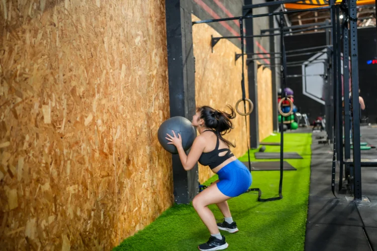 Female athlete performing wall ball exercise during HYROX training highlighting fatigue injury risk.