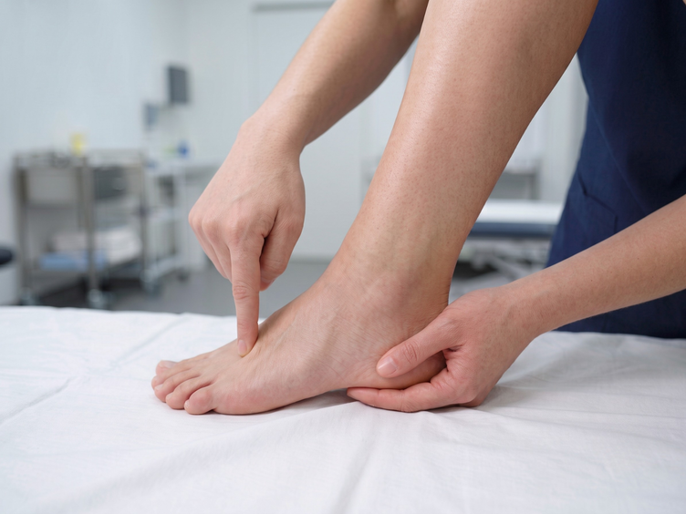 Clinician pressing one point on a patient's foot to check a stress fracture.