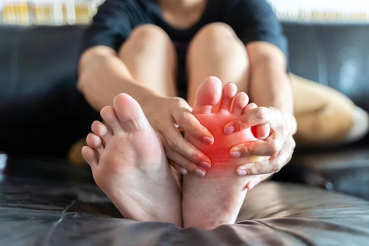 Close-up of person holding foot with redness, resting to recover from metatarsal stress fracture.