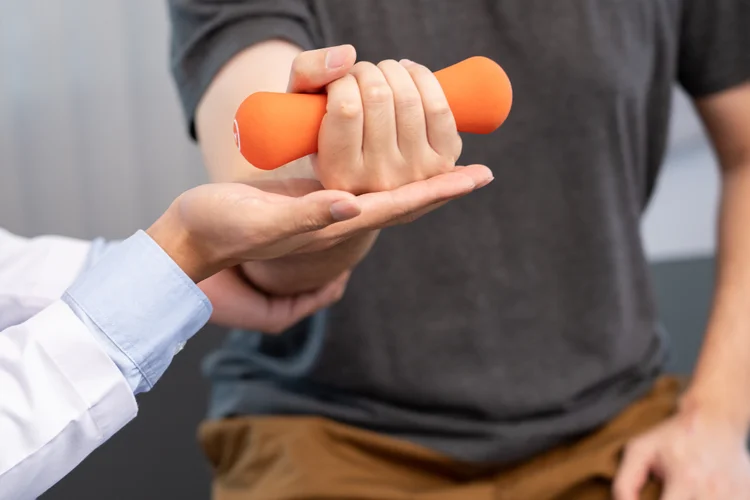 Hand specialist supporting patient doing hand strength test to assess grip weakness symptoms.