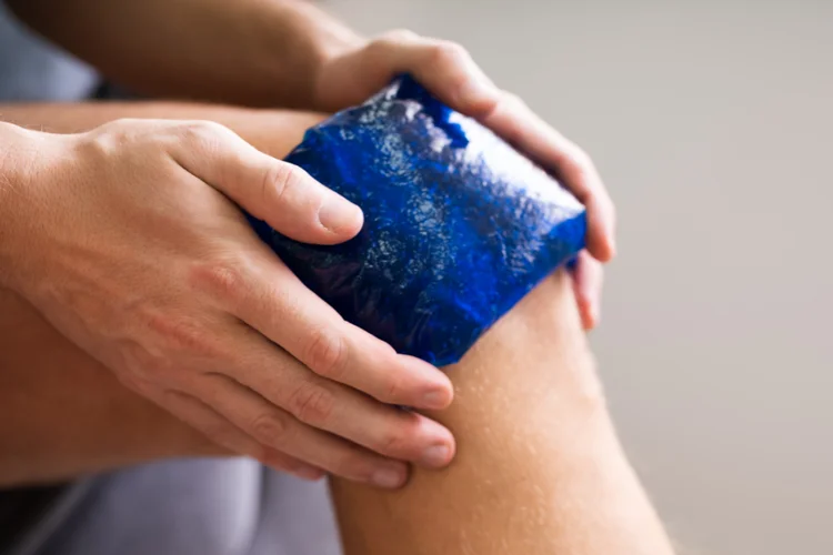 Person applying ice pack to knee as an alternative to anti-inflammatory medication.