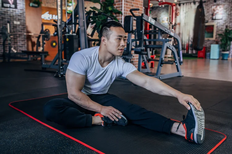 Male athlete stretching hamstring and calf as part of warm-up to prevent HYROX training injuries.