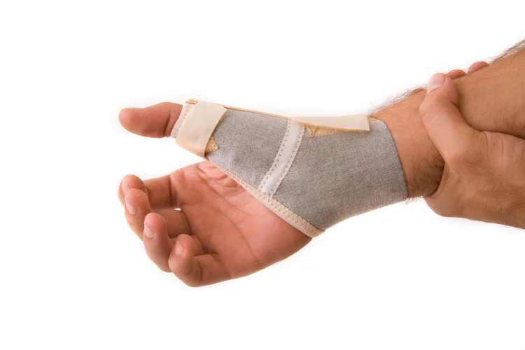 Male patient wearing thumb and wrist splint for upper limb pain treatment at orthopaedic clinic.