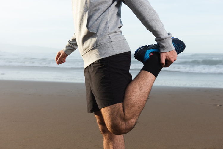 Man doing a standing quadriceps stretch post-run to ease front thigh tightness and support recovery.