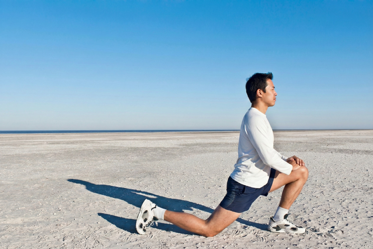Man holding a hip flexor stretch after running to release front-of-hip tension and improve mobility.