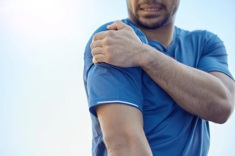 Man holding shoulder in pain after possible dislocation from trauma or sports injury.