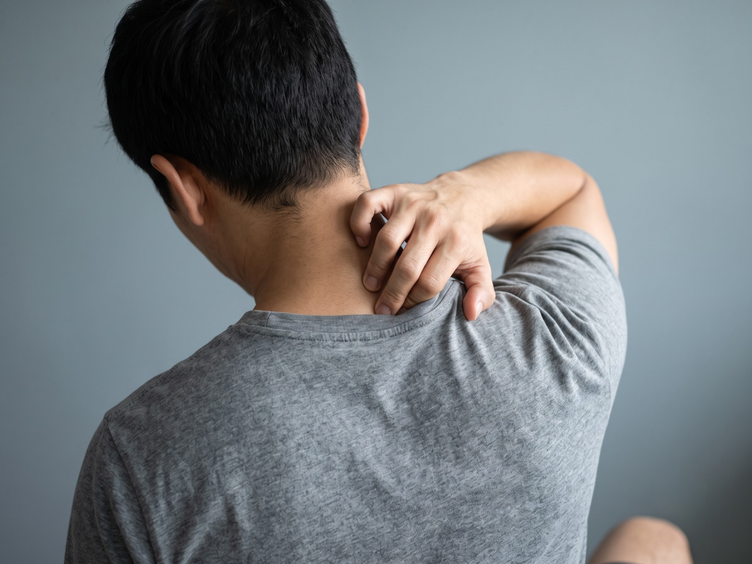 Man gripping his upper trapezius to ease neck and shoulder tension.