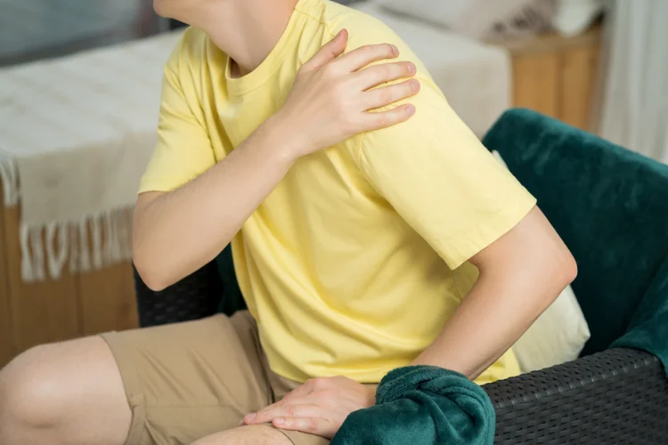 Man holding shoulder in pain, showing signs of labral tear with discomfort and weakness.