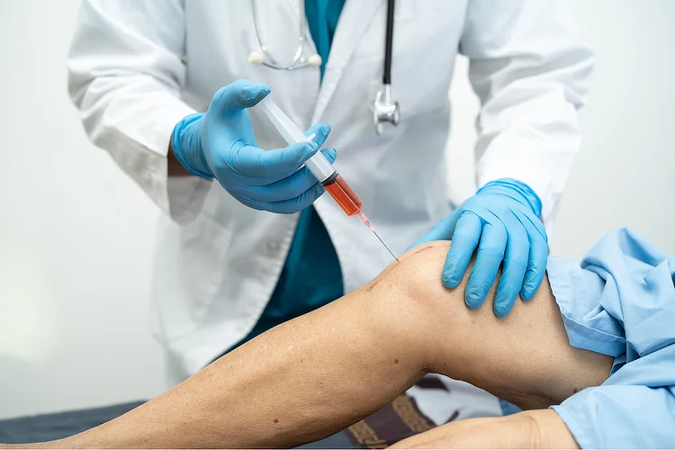 Orthopaedic specialist administering PRP injection into patient’s knee for joint pain.