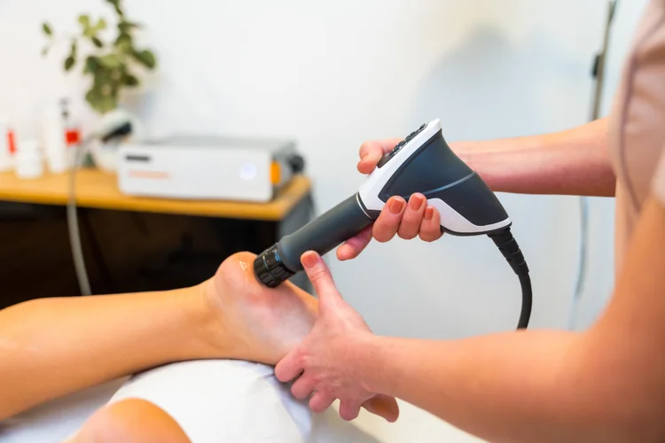 Shockwave therapy device applied to foot for treatment of heel pain related to plantar fasciitis.