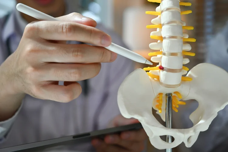 Spine specialist explaining spinal condition with anatomical model.