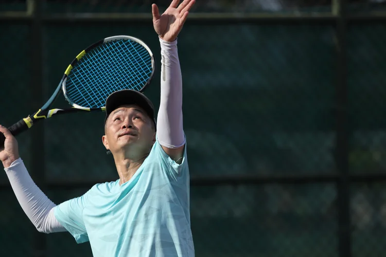 Tennis player serving overhead, showing motion linked to SLAP tear from shoulder stress.