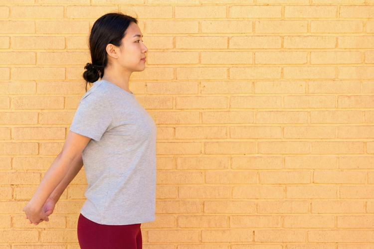 Woman doing chest and shoulder stretch post-run to open the upper body and ease muscle tightness.