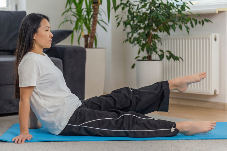 Woman doing seated leg raises to strengthen quadriceps and support better knee endurance for skiing.