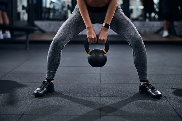 Woman lifting kettlebell to build core and back strength to prevent back pain.