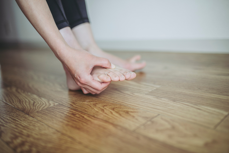 Woman pressing between third and fourth toe due to pain caused by morton's neuroma condition.