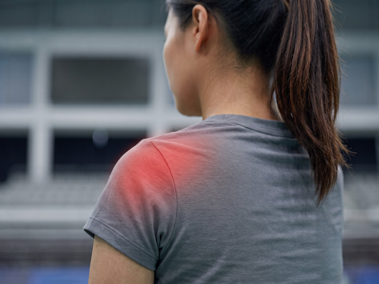 Female athlete with shoulder pain highlighted in red over the rotator cuff.